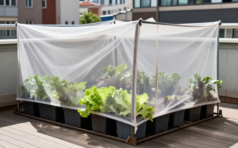 Huerto urbano en terraza con malla de sombreo protegiendo las plantas del sol